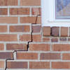 long jagged cracks starting at the corner of a window along a brick wall on a Corona home